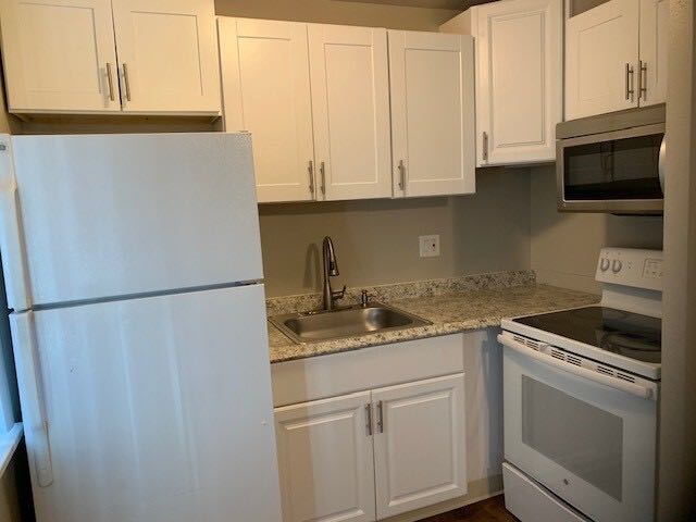 Renovated kitchen with granite counters, shaker cabinets and stainless microwave